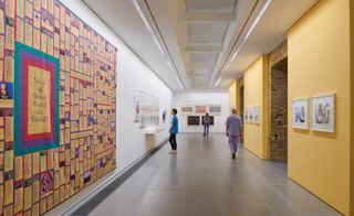 people walking down a corridor with art on walls