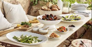 Outdoor dining table dressed with whote servingware to support the quiet luxury garden trend