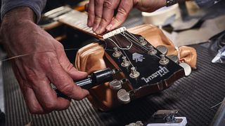 Best guitar cleaning kits and tools: Man restringing a Gibson guitar 