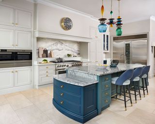 Marble island with blue cabinetry and chairs, in a large neutral scheme