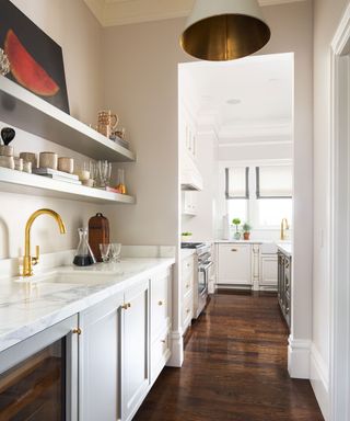 Modern kitchen and utility room, dark wooden flooring, white cabinetry, marble countertop