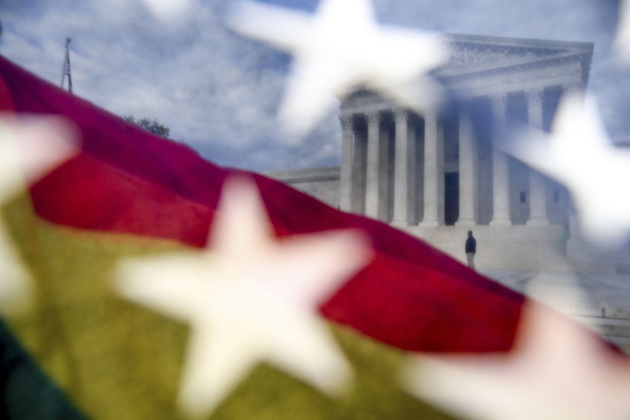 A rainbow flag waves in the wind outside the Supreme Court.