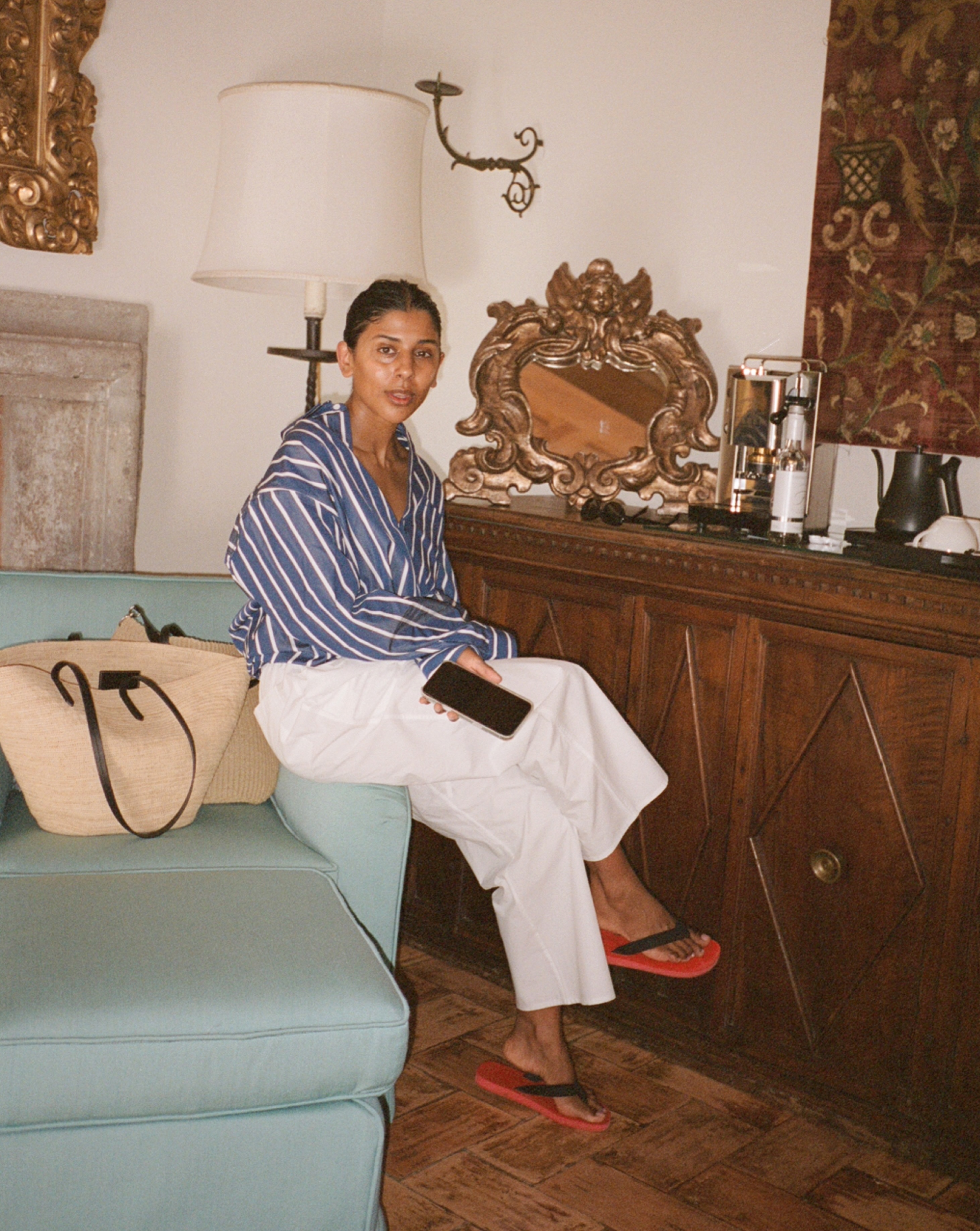 Monikh in striped shirt, white trousers and with a raffia tote