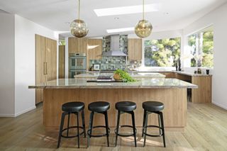 A modern kitchen with a marble island and bar stools