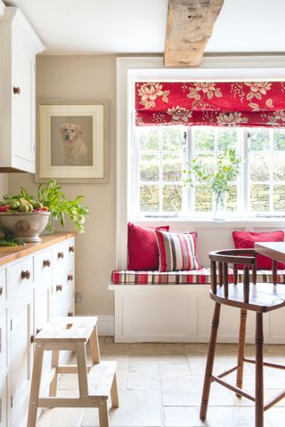 white kitchen with wooden worktops and cabinetry plus window seat with red blinds