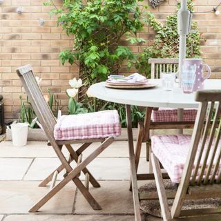 A patio with wooden outdoor furniture and gingham seat cushions