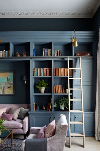 Blue bookshelf with ladder and sofa area