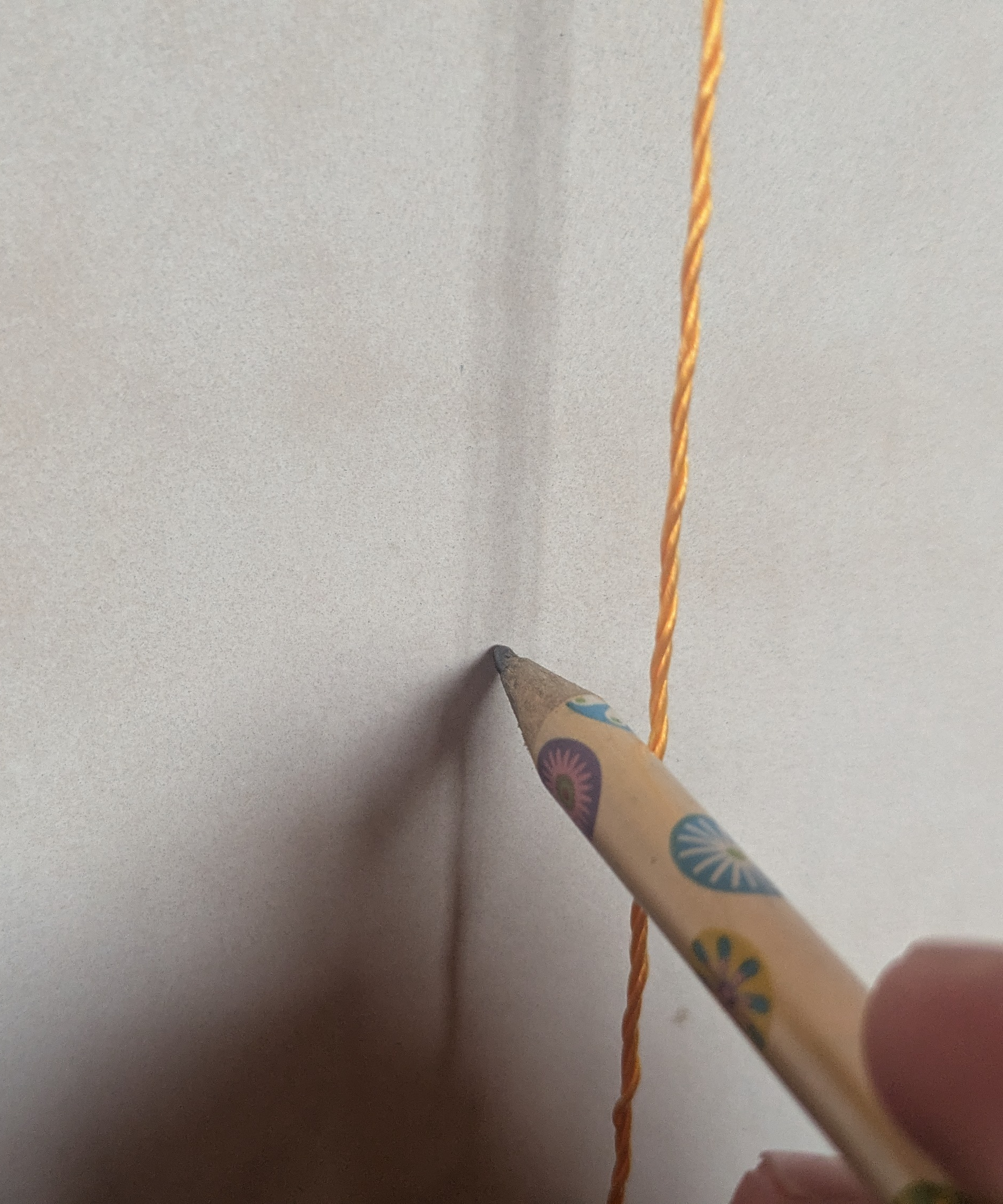 A pencil marking a wall next to a taut piece of string