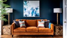  picture of burnt orange velvet sofa in a navy room with wooden coffee tables to support an expert guide on how to clean a velvet sofa