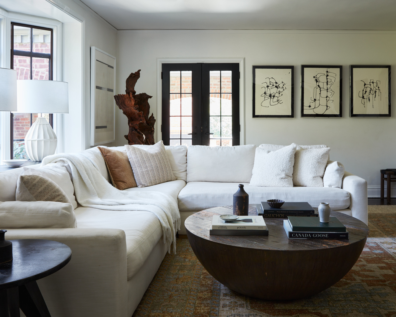 White sectional couch in living room with wooden coffee table and modern art on wall