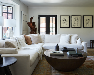 Λευκός τμηματικός καναπές στο σαλόνι με ξύλινο τραπεζάκι και μοντέρνα τέχνη στον τοίχο