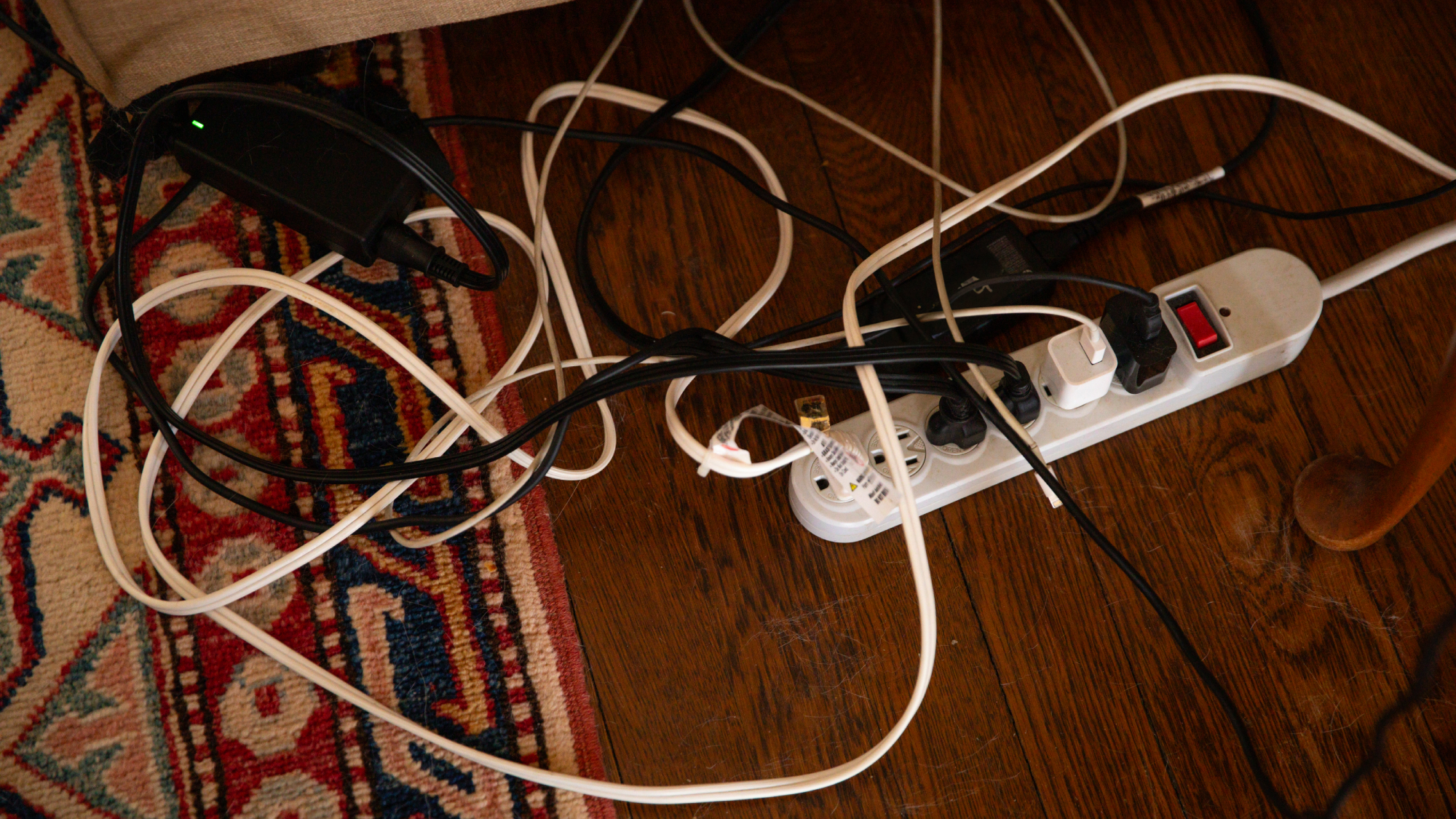 rug on wooden floor with extension lead and lots of messy cables