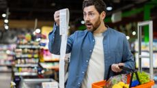 Male grocery shopper looking at the contents of his receipt in disbelief