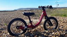 Prevelo Alpha Zero balance bike in red set against a seaside backdrop