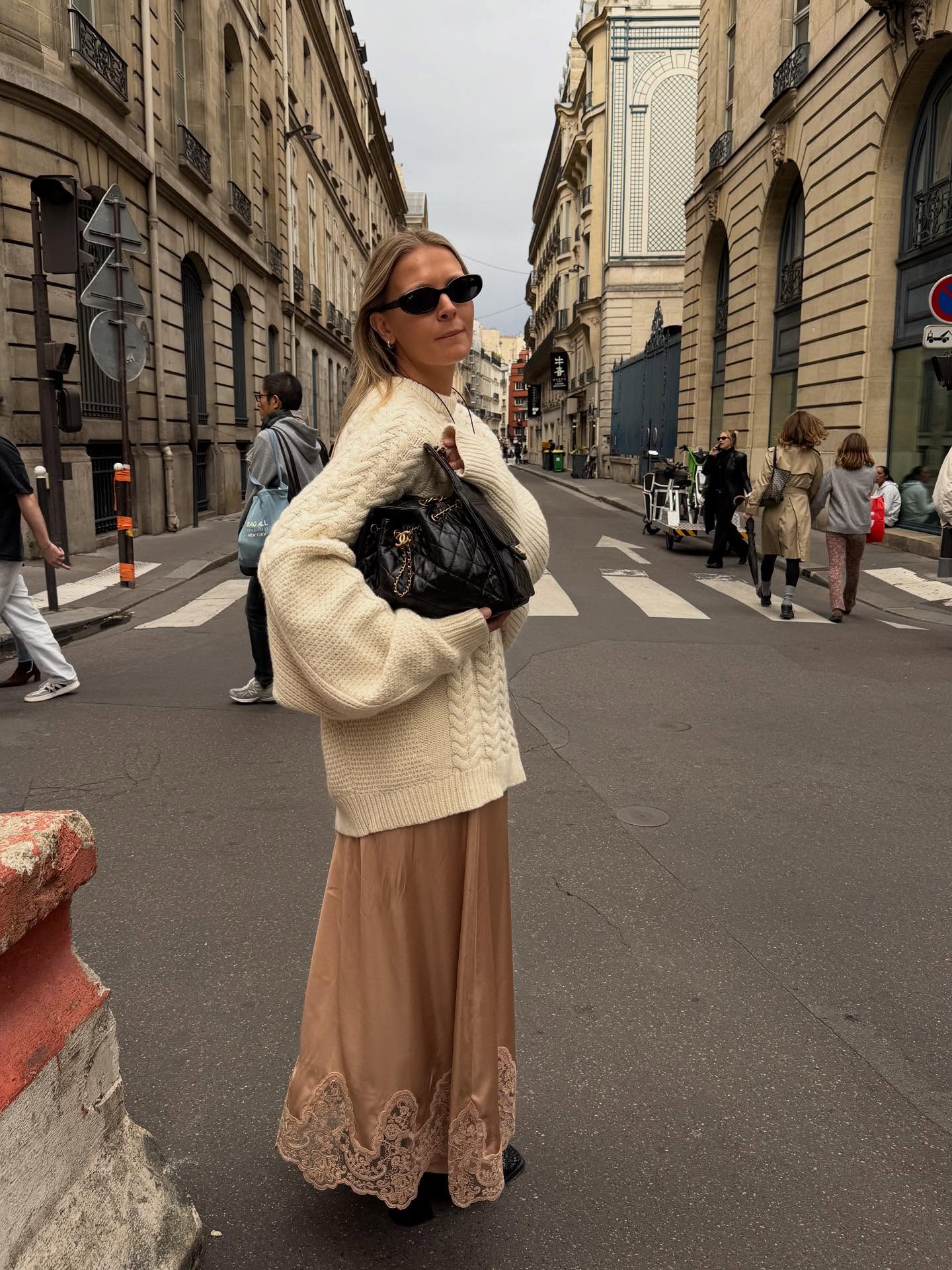 An image of @holliemercedes wearing a Chanel 25 bag, oversized jumper and lace-trim dress, one of the biggest 2026 office outfit trends.