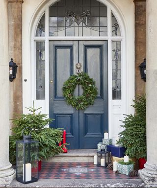Festive blue front door with wreath and christmas trees