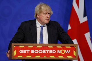 Boris Johnson standing in from of a lectern reading Get Boosted Now