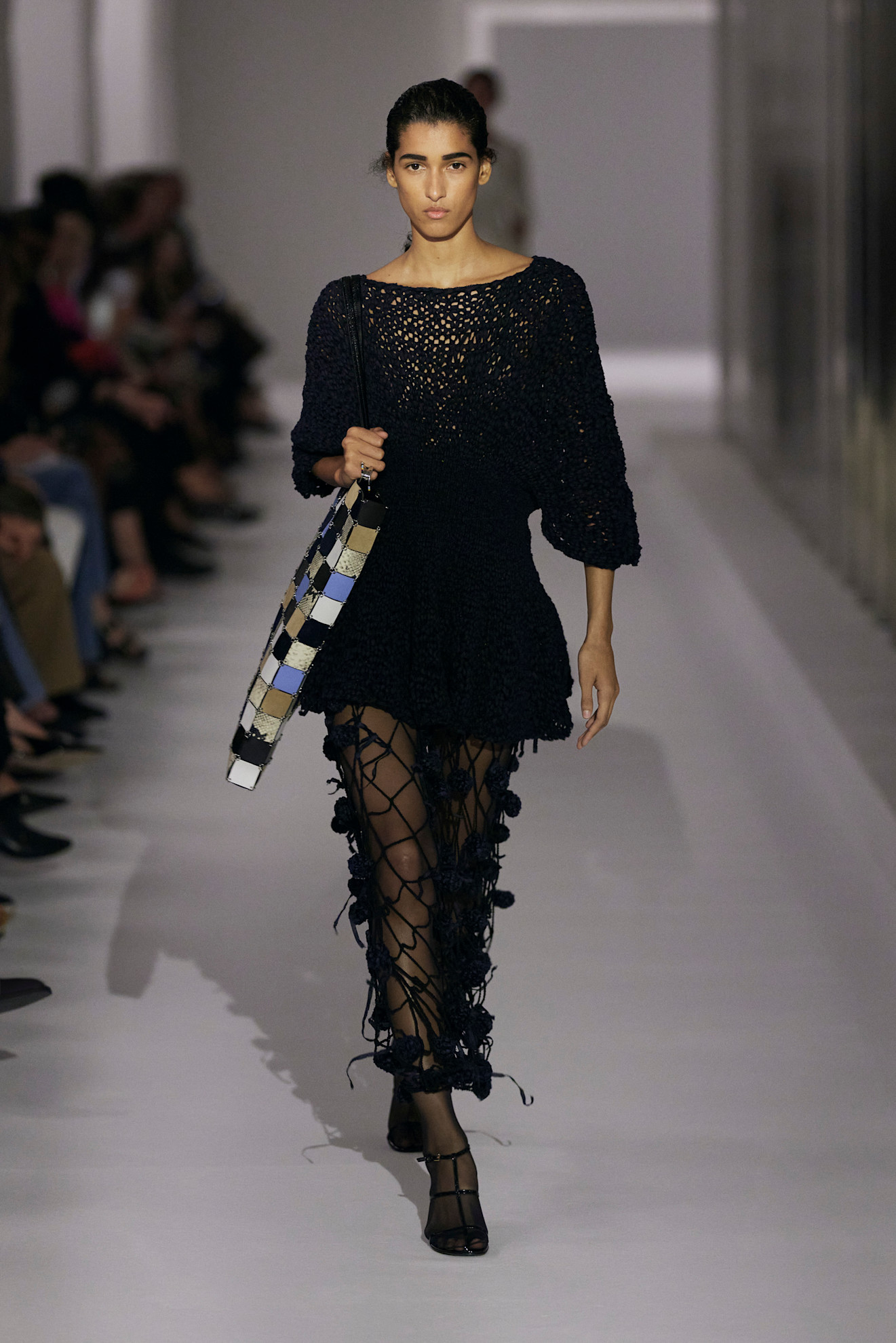 A model at the Khaite show during S/S 25 fashion week wearing a loose-knit cotton sweater with a crochet skirt and tights.