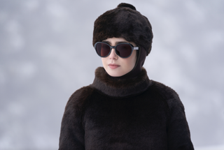 Lily Collins wears a fur coat and a fur hat with oversize sunglasses.