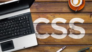 CSS letters on wooden bench with a laptop
