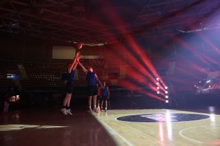 An image shot at a high ISO, cleaned up in-camera with Canon's AI denoise feature on the Canon EOS R5 Mark II. The image shows two basketball players competing on a court illuminated by artistic laser lights