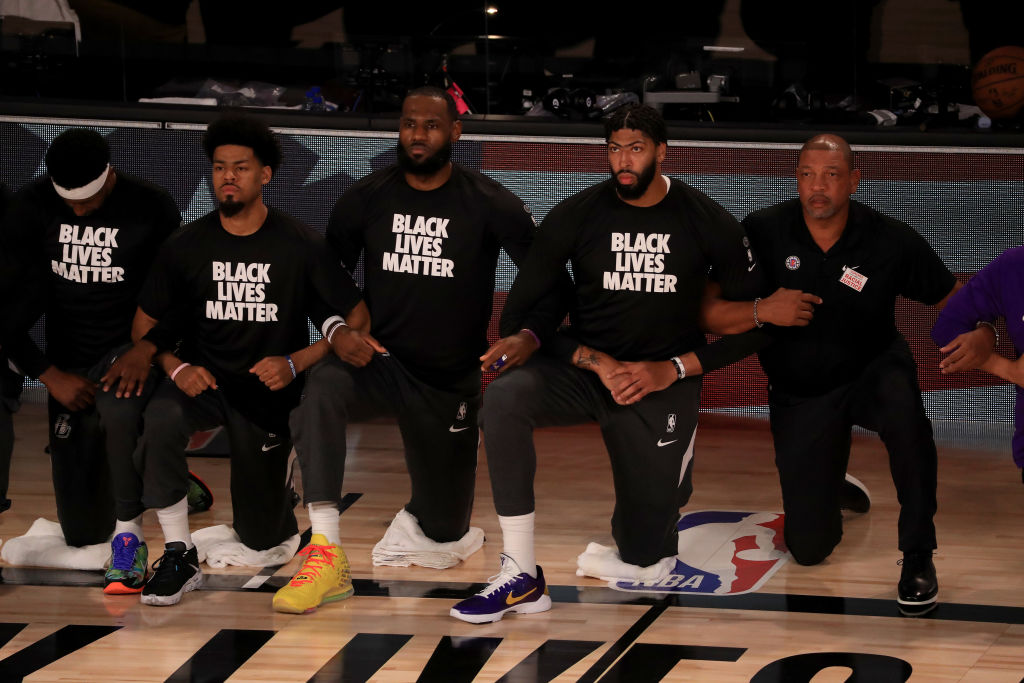 LeBron James #23 and Anthony Davis #3 of the Los Angeles Lakers in a Black Lives Matter Shirt kneel with their teammates during the national anthem prior to the game against the LA Clippers a