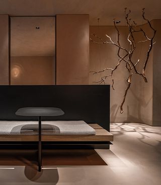 A minimalist restaurant whose interior decor is modelled of earthy tones of brown, grey, and cream features linearly designed furniture and a plant installation hanging from the ceiling.