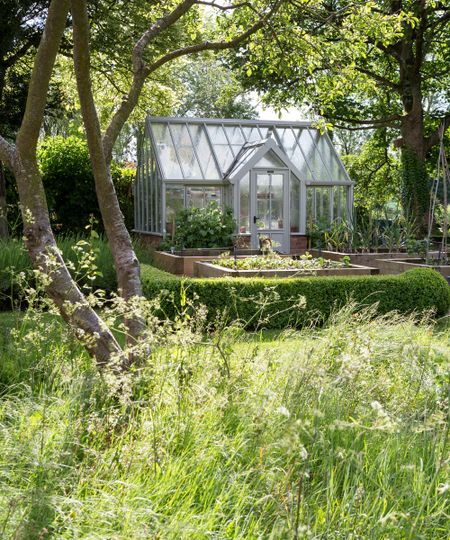 traditional greenhouse surrounded by a vegetable garden
