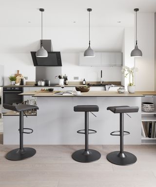 A set of three powder-coated steel bar stools in kitchen with trio of concrete grey pendant ceiling lights