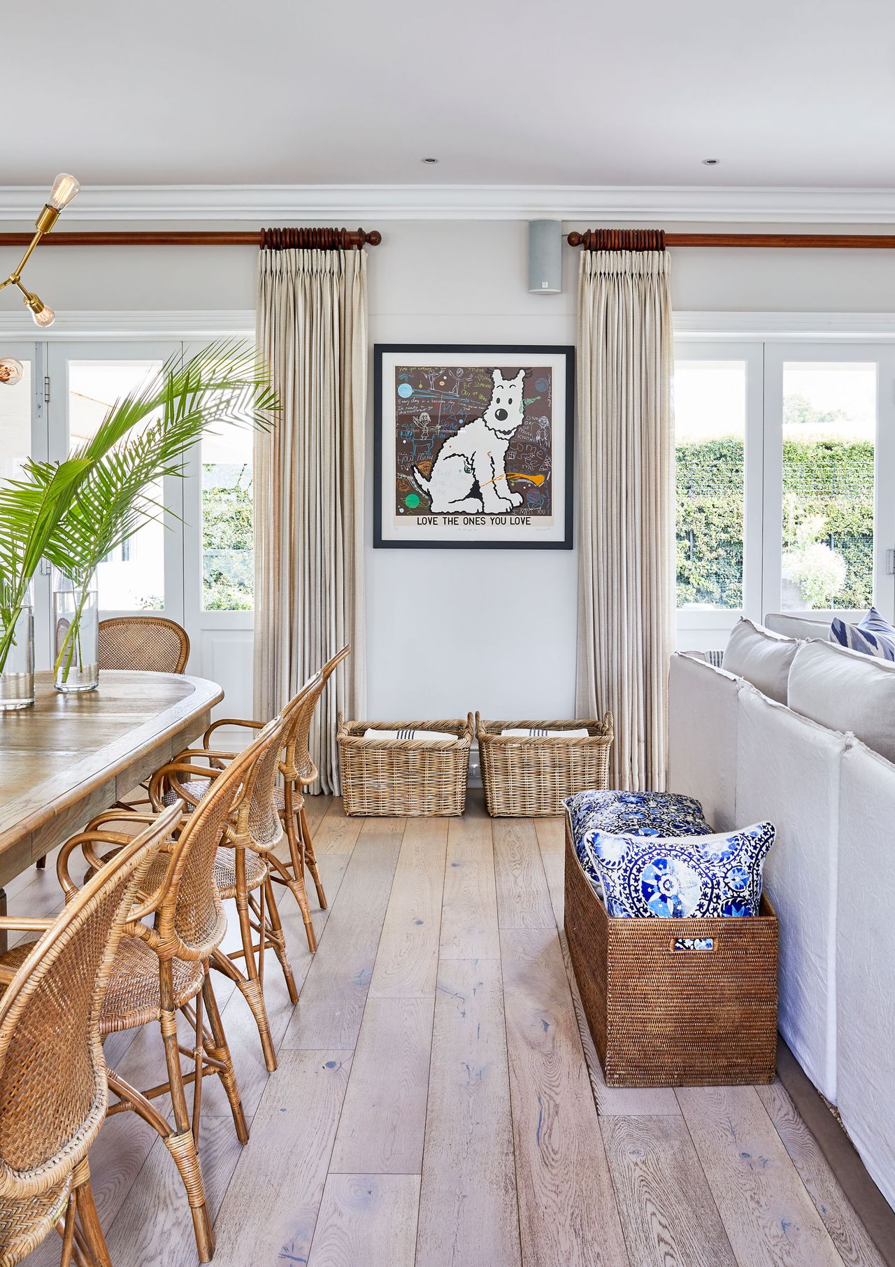 Open plan dining room and living room, with long dining table and wooden chairs, white sofa