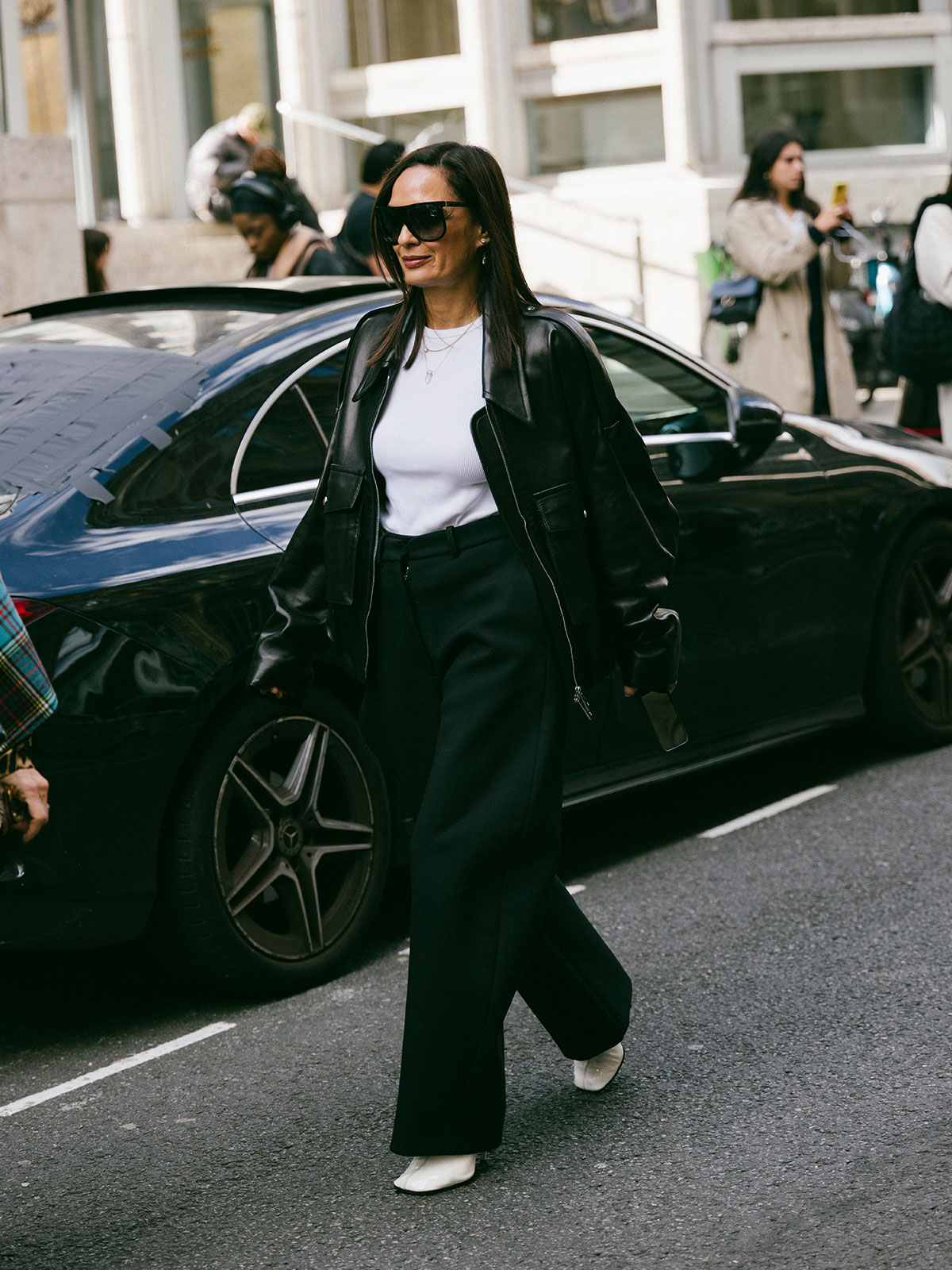 Woman wearing a leather jacket, a white tee, and black trousers.