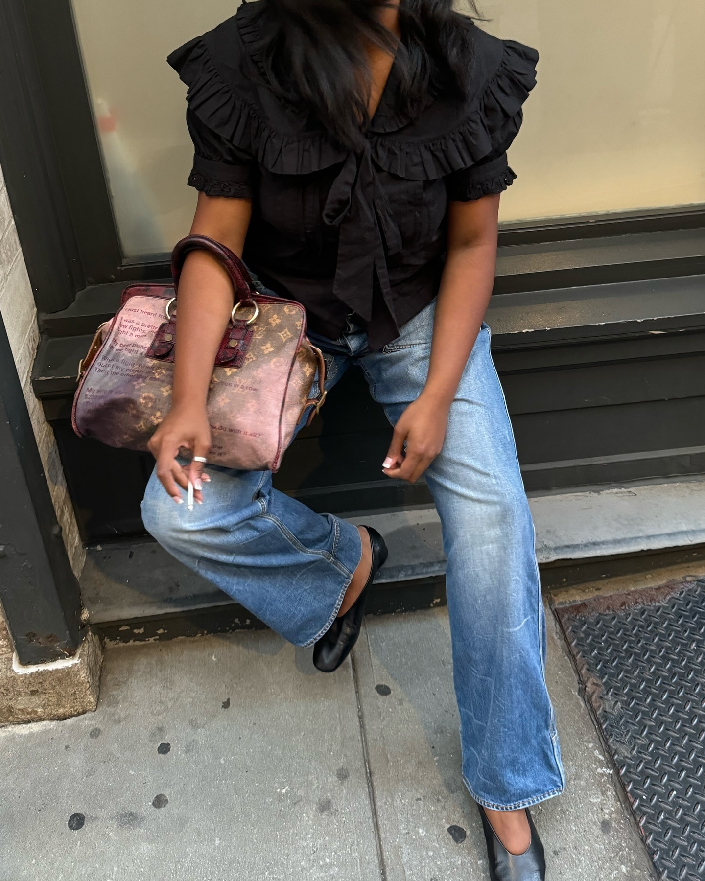 A woman wearing a black puff sleeve top and blue jeans.