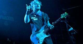 Zach Myers of Shinedown is bathed in blue stage lights and plays his custom-relic'd Silver Sky.
