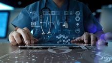 A medical professional working on a digital device with icons floating in the air.