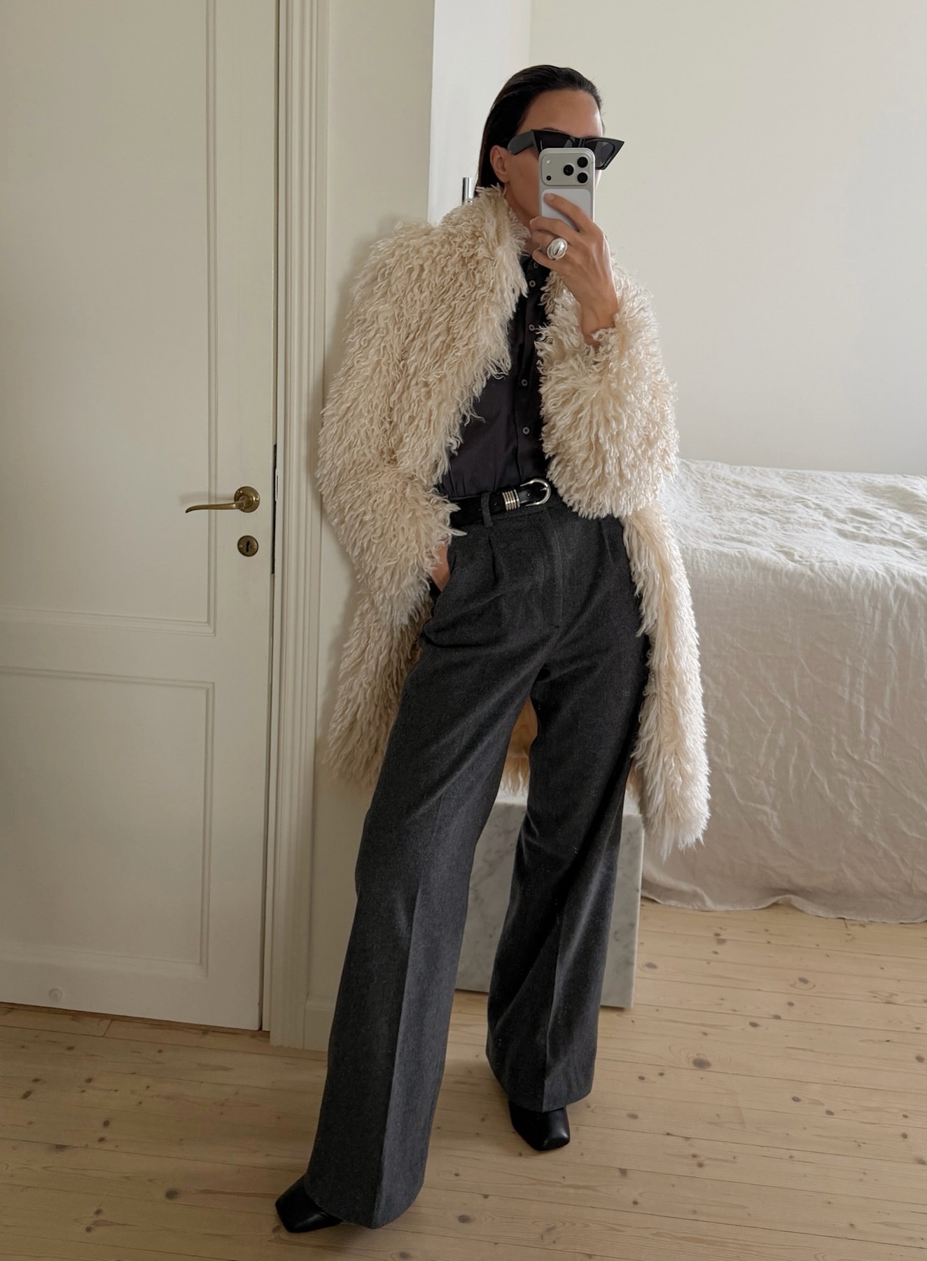 An image of @johannapiispa wearing a grey button-down, grey pleated trousers and a faux fur coat.