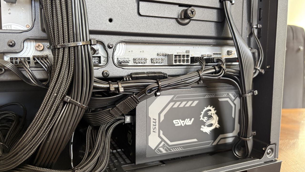 Inside an MG-1 MK.II computer case showing detailed cable management and connections to a PSU with a dragon logo. The setup is neat and organized.