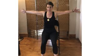 Nicola Geismar performing seated chest stretch yoga move in chair