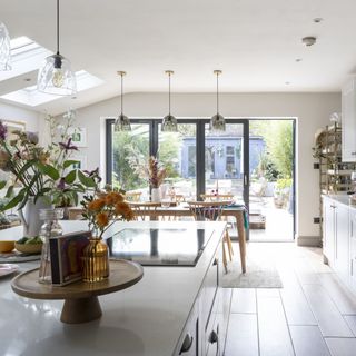 open plan kitchen diner with island, white cabinets, pendant lights and floral decor