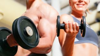 Man and woman holding a dumbbell in hand performing a bicep curl