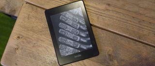 En Amazon Kindle 2018 ligger med skärmen vänd uppåt på ett träfärgat bord..