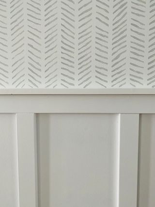 DIY stenciling in a herringbone pattern, on a white entryway wall