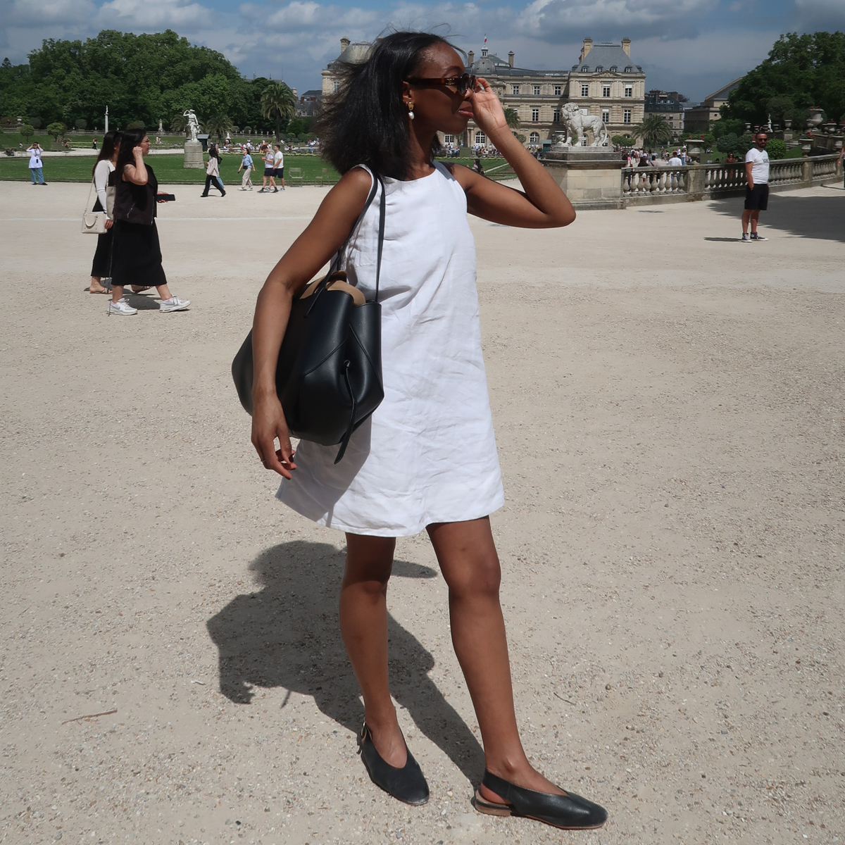 Avalon Afriyie wears a white linen dress and black slingback flat shoes