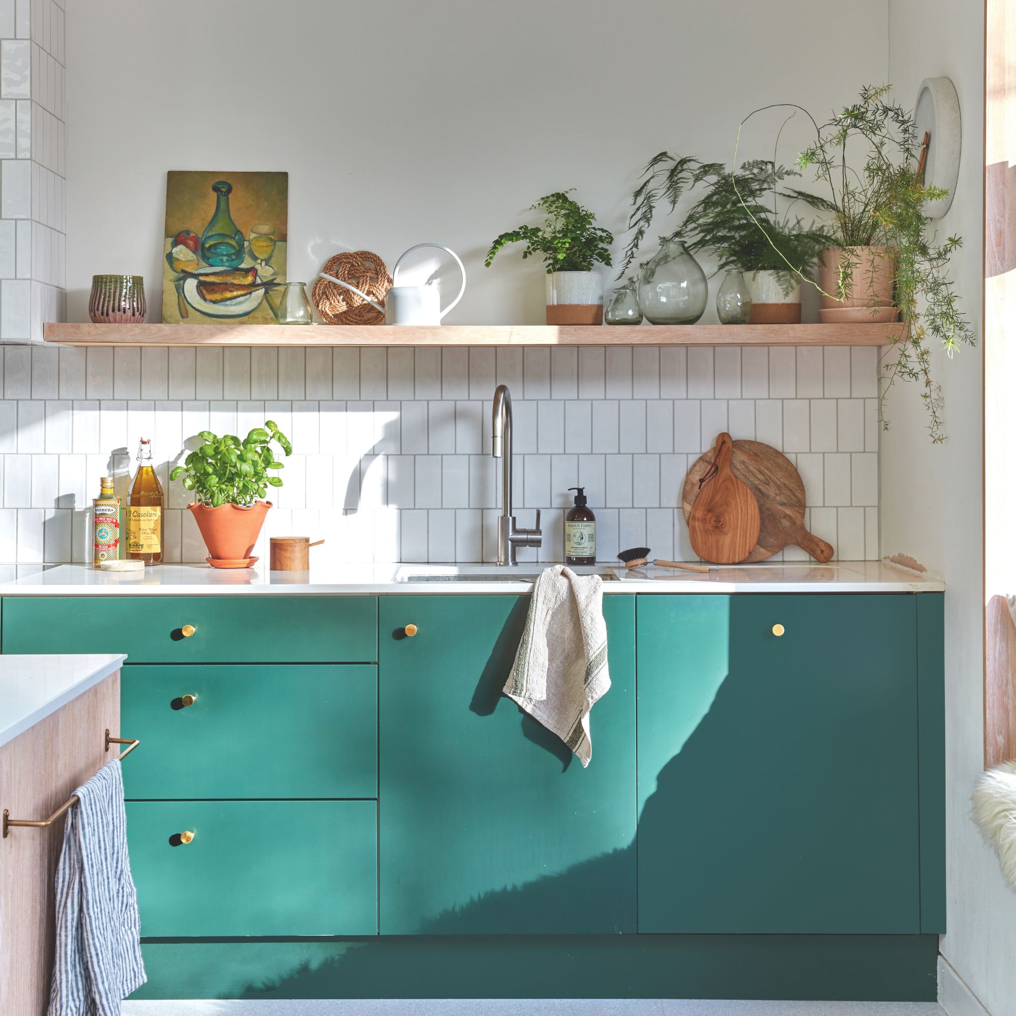 Kitchen with white tiles on the wall and green teal cabinets under the sink