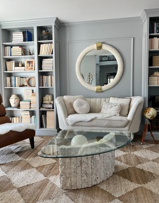 Ikea billy bookcases on the left and right side of a living space with a sofa in the middle and a large glass coffee table.