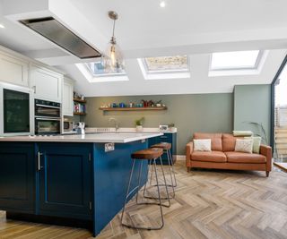 kitchen extension with blue island, ceiling mounted extractor fan above hob, three large skylights, wooden floor and patio doors