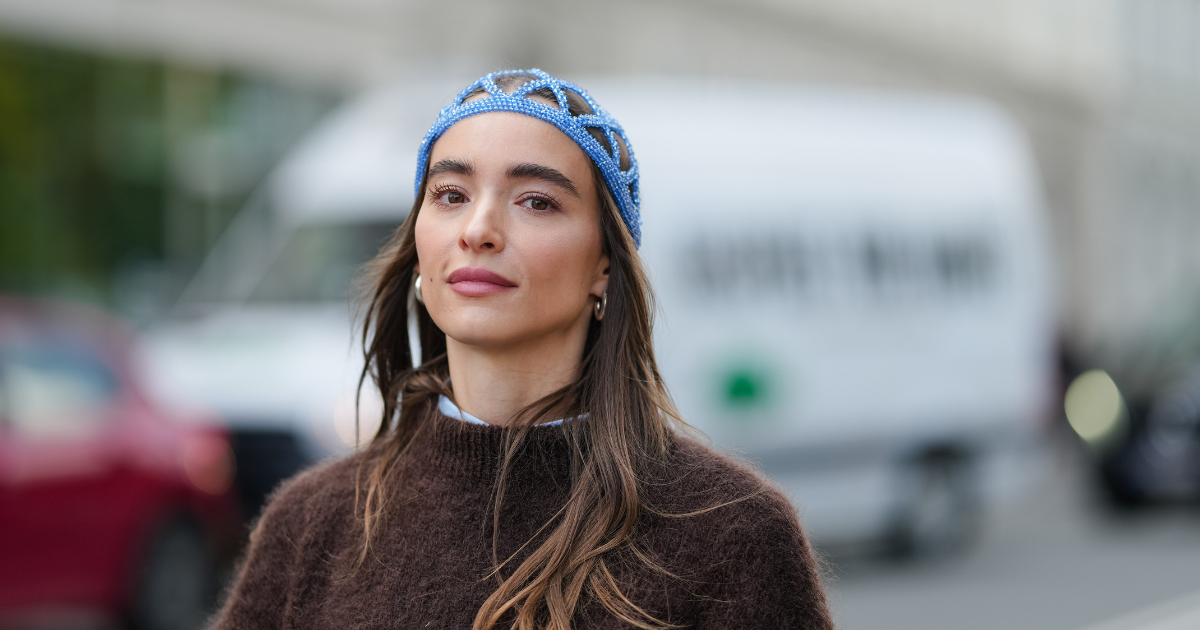 Permanent make-up A guest wears a blue patterned pearls headband hat and has long, loose hair. The outfit includes a dark brown, textured sweater layered over a light blue collared shirt with visible cuffs, outside Munthe, during Copenhagen Fashion Week, on August 06, 2025