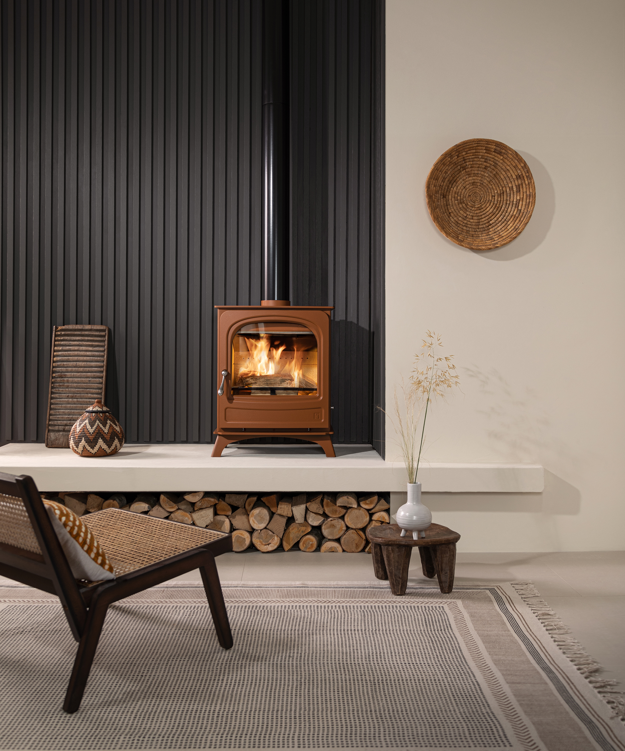 rust coloured log burning stove on raised hearth with log storage beneath