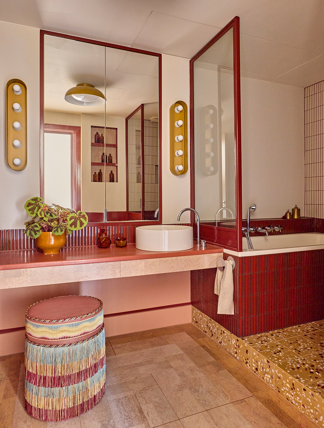 pink bathroom with red tiles terrazzo and wood floor, and a fringed stool