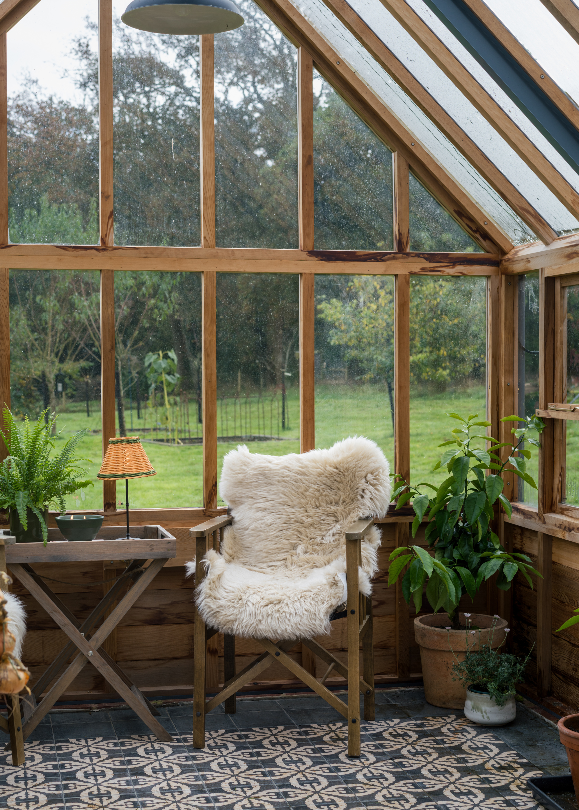 A wooden chair with a faux fur furnishing in a greenhouse
