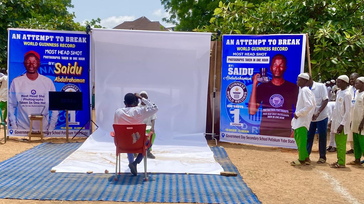 Photographer Saidu Abdulrahaman takes a portrait on a white backdrop while a line of students wait their turn